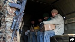 FILE - A pro-Russia rebel guards captured Ukrainian soldiers seated on a truck in Novohryhorivka, Donetks region, eastern Ukraine, Feb. 27, 2015.