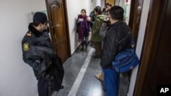 FILE - An Azerbaijani policeman, left, guards as journalists gather at the Radio Free Europe headquarters in Baku, Dec. 26, 2014.