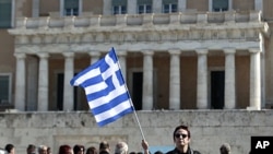 A woman raises a Greek flag during an anti-austerity rally in front of the parliament in Athens February 19, 2012.