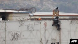 Miembros de la policía ecuatoriana son vistos junto al cuerpo de un recluso en el techo de un pabellón de la prisión Guayas 1, en Guayaquil, Ecuador, el 13 de noviembre de 2021.