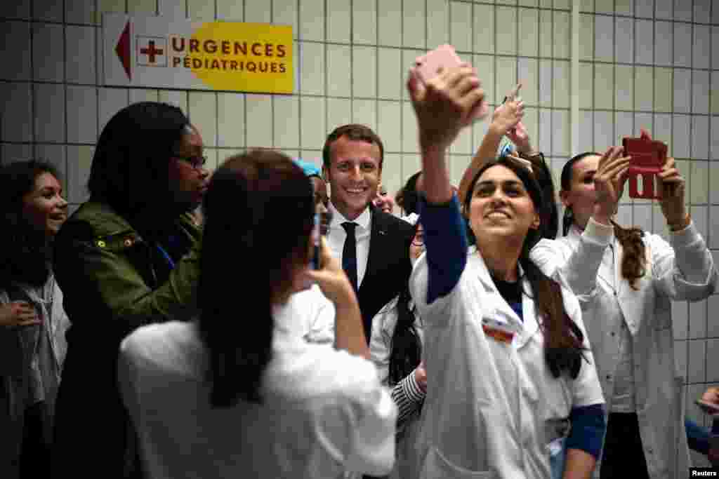 French President Emmanuel Macron (C) poses for a selfie with medical staff members as he visits the Robert-Debre pediatric hospital in Paris.