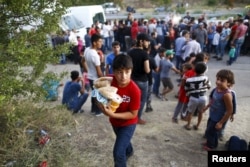 FILE - A migrant child carries food given by a local NGO near Edirne in Turkey, as they rest from their travel towards the Greek border, September 17, 2015.