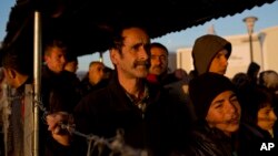 Syrian refugees stand in line for food distributed at a refugee camp in the Greek-Macedonian border near the village of Idomeni, Feb. 25, 2016.