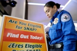 A Transportation Security Administration employee stands at a booth to learn about a food stamp program at a food drive at Newark Liberty International Airport, Jan. 23, 2019, in Newark, N.J.