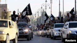 FILE - Islamic State fighters parade on military vehicles along the streets of Syria's northern Raqqa province.