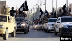 FILE - Islamic State fighters parade on military vehicles along the streets of Syria's northern Raqqa province in June 30, 2014.