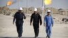 Des travailleurs irakiens marchent dans le champ pétrolifère de West Qurna, dans la province de Bassorah, en Irak, le 28 novembre 2010.