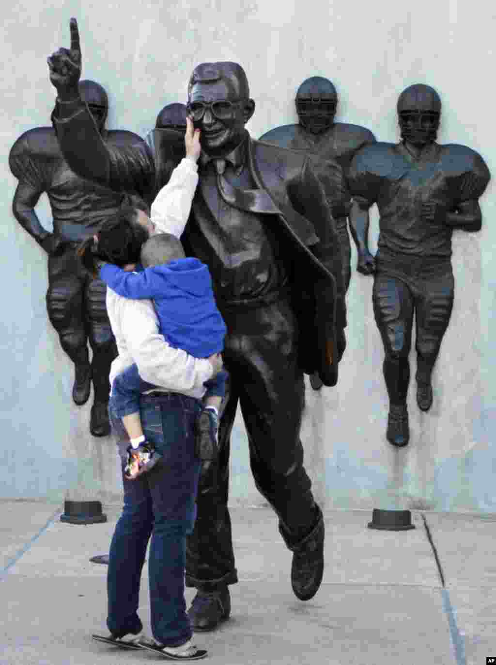 Ashley Buchan holds her 4-year-old nephew Caleb Anthony, as she reaches to touch the face of the statue of Penn State football coach Joe Paterno outside Beaver Stadium, October 8, 2010. (AP)