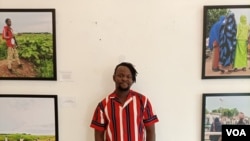 Nigerian photojournalist Damilola Onafuwa poses with some photos he took from conflict areas for the Center for Civilians in Conflict, in Abuja, September 21, 2021. (Timothy Obiezu/VOA)