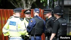 A group of police officers stand outside flats in Hulme, Manchester, May 25, 2017. 