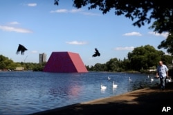 People walk past 'The London Mastaba' by artist Christo as it sits on the Serpentine in Hyde Park, London, Britain, June 18, 2018.