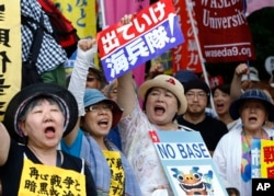Anti-U.S. base protesters shouts slogans at a rally in front of the National Diet building in Sunday, June 19, 2016.