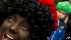 FILE: A "Black Pete" interacts with children during the arrival of Sinterklaas in Maassluis, Netherlands, Saturday, Nov. 12, 2016. "Black Pete" is often played by white people with their faces daubed in dark makeup.Netherlands Black Pete Protest