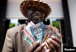 A man from South Sudan displays new currency notes outside the Central Bank of South Sudan in Juba, July 18, 2011.