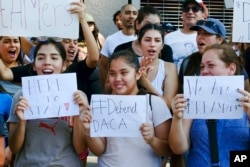 FILE - Supporters of the Deferred Action for Childhood Arrivals, or DACA, chant slogans and holds signs while joining a Labor Day rally in downtown Los Angeles on Sept. 4, 2017.