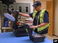 FILE -- National Transportation Safety Board engineer William Tuccio on October 4, 2016, removes the event recorder memory board and video recorder hard drive, recovered from the N.J. Transit train that crashed into a New Jersey rail station.