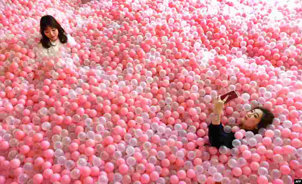 A visitor to Sugar Republic takes a selfie as she reclines in a display of balls resembling lollipops in Melbourne.