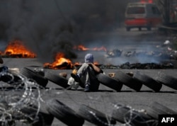 Palestinian men burn tires during a protest in the West Bank city of Ramallah, April 6, 2018.
