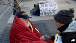 FILE - A homeless Korean War veteran speaks with an outreach coordinator on a sidewalk in Boston, Massachusetts.