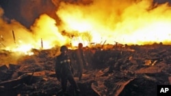 Firemen look around at the scene of an explosion at a warehouse in Rangoon, Burma, December 29, 2011.