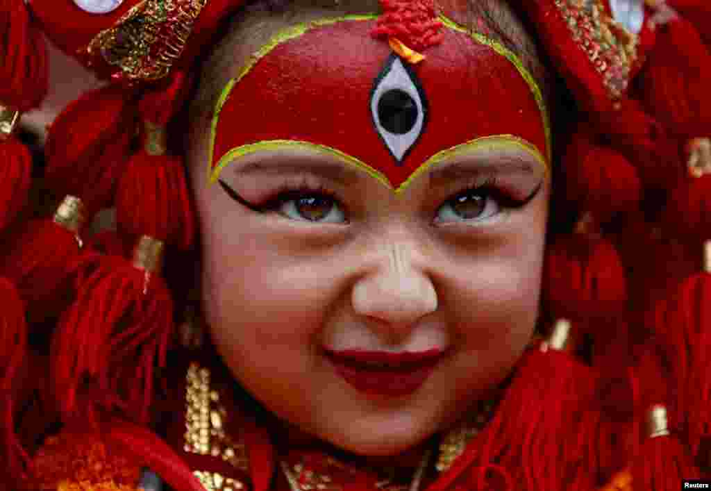 A young girl dressed as the Living Goddess Kumari participates the Kumari Puja festival, in which young girls pose as the Living Goddess Kumari and are worshipped by people in belief that their children will remain healthy, in Kathmandu, Nepal.