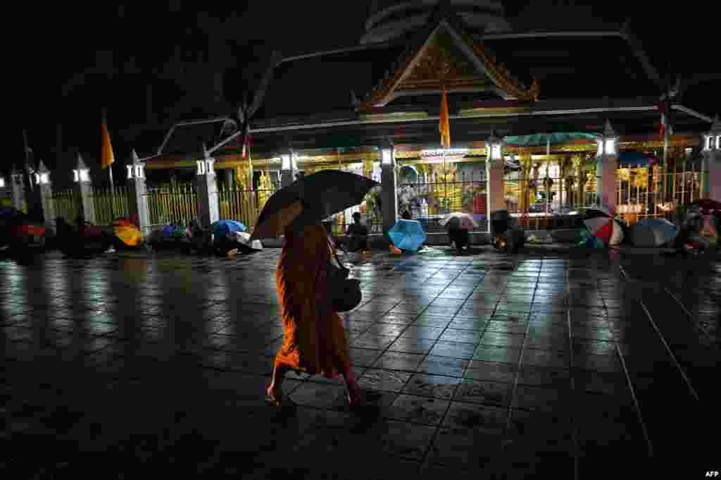 A Buddhist monk walks past people lining up overnight for free COVID-19 testing at Wat Phra Sri Mahathat Woramahawihan in Bangkok, Thailand.