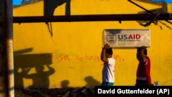 Typhoon Haiyan survivors help carry USAID donated food after a U.S. military helicopter unloaded it in the destroyed town of Guiuan, Philippines on Thursday, Nov. 14, 2013. 