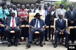 FILE - South Sudan's President Salva Kiir, center, laughs with First Vice President Riek Machar, left, and Vice President James Wani Igga, right, while cabinet members stand behind them, after the first meeting of a new transitional government of national unity, in Juba, April 29, 2016. (J. Patinkin/VOA)