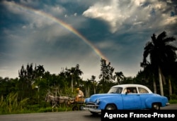 FILE - An old American car is seen in Havana as a rainbow appears in the sky, on February 3, 2022.
