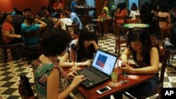  三名越南女孩在河內一家咖啡館利用便攜電腦和智能手機上網。