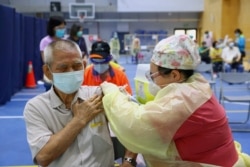 FILE - A medical worker administers a dose of the AstraZeneca vaccine to a man during a vaccination session for elderly people over 75 years old, at a stadium in New Taipei City, Taiwan June 25, 2021.