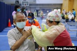 FILE - A medical worker administers a dose of AstraZeneca vaccine to a man during an immunization session for people over the age of 75, at a stadium in New Taipei City, Taiwan, June 25, 2021.