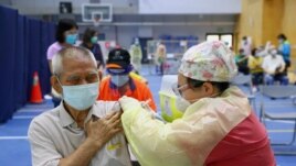 FILE - A medical worker administers a dose of the AstraZeneca vaccine to a man during a vaccination session for elderly people over 75 years old, at a stadium in New Taipei City, Taiwan June 25, 2021.