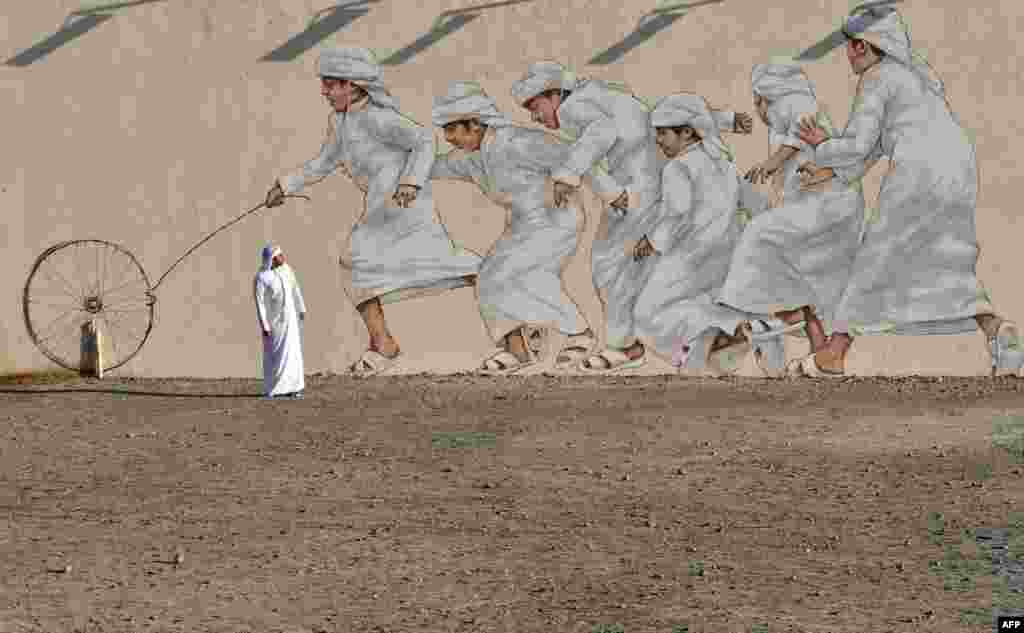 A man walks past a giant mural in Dubai, United Arab Emirates