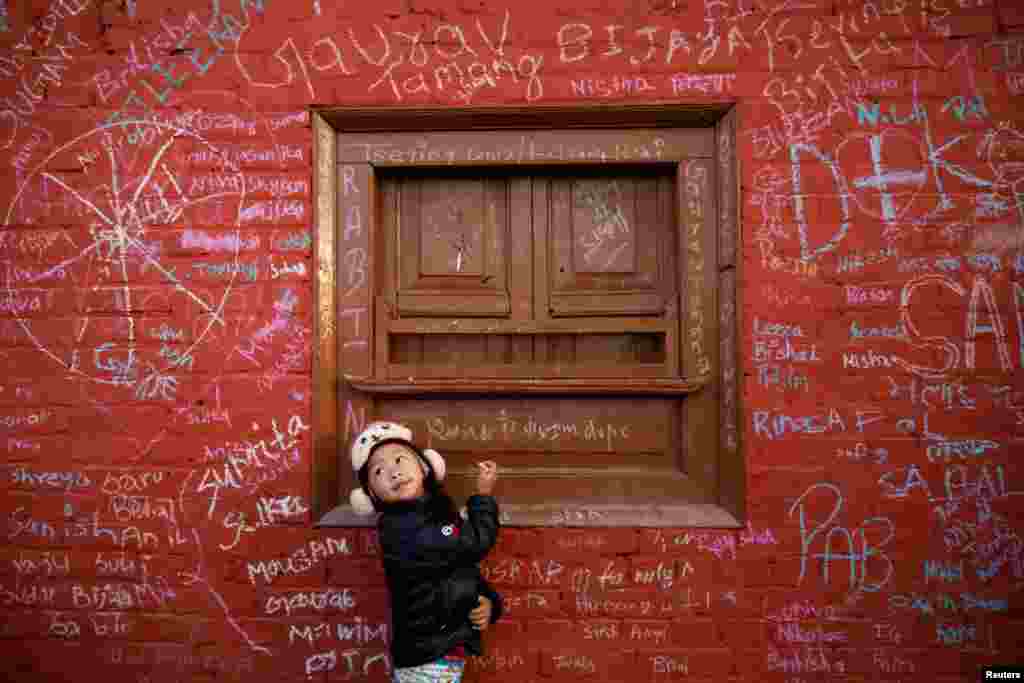 A girl writes on the wall of a Saraswati temple during the Shreepanchami festival dedicated to goddess of education Saraswati in belief that the goddess will help devotees excel in education, in Kathmandu, Nepal.