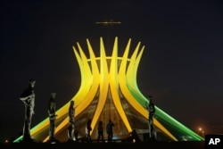 FILE - The Metropolitan Cathedral is illuminated in Brazil's national colors in honor of the World Cup, in Brasilia, Brazil, June 6, 2014. (AP Photo/Eraldo Peres)