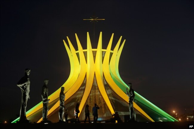 FILE - The Metropolitan Cathedral is illuminated in Brazil's national colors in honor of the World Cup, in Brasilia, Brazil, June 6, 2014. (AP Photo/Eraldo Peres)