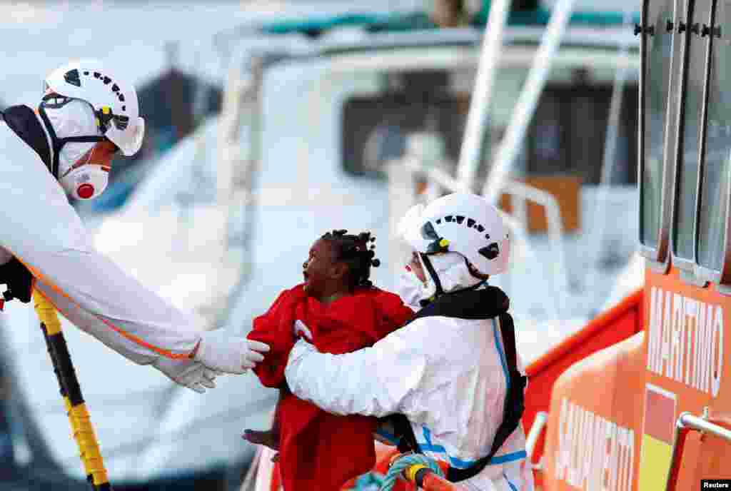 Rescuers help a migrant child to disembark from a Spanish coast guard vessel, in the port of Arguineguin, in the island of Gran Canaria, Spain, Oct. 10, 2021.