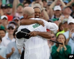 Tiger Woods reacts with his caddie Joe LaCava as he wins the Masters golf tournament, April 14, 2019, in Augusta, Ga.