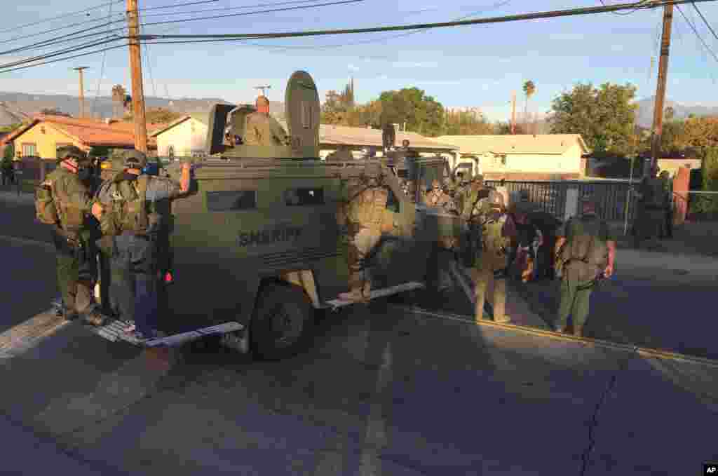 Petugas penegak hukum dengan kendaraan berlapis baja mencari area tempat polisi menghentikan mobil SUV tersangka di San Bernardino, California (2/12). (AP/Chris Carlson)