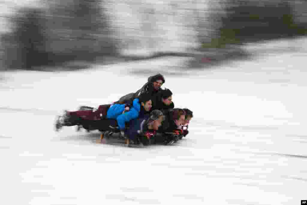 Youngsters slide down hill on sledges after a snowfall at the Woluwe park in Brussels, Belgium.