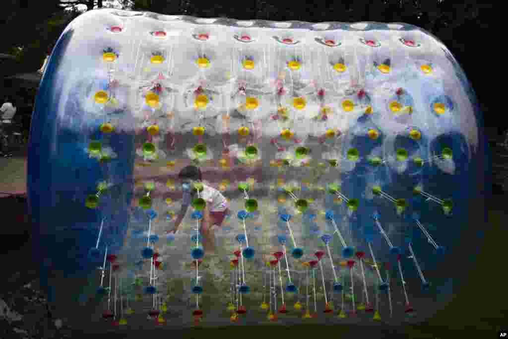 A boy wearing a face mask plays inside an inflatable tube at a public park in Beijing, China, July 11, 2020.