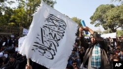  FILE - An Afghan student waves a white Taliban flag at a rally in Kabul, Afghanistan, Oct. 25, 2014.