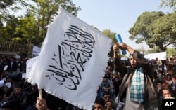 FILE - An Afghan student waves a white Taliban flag at a rally in Kabul, Afghanistan, Oct. 25, 2014.