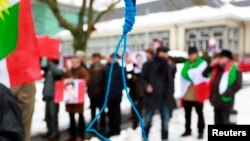 FILE - Iranian exiles shout slogans in front of a mock gallows to protest against executions in Iran during a demonstration outside the Iranian embassy in Brussels, Dec. 29, 2010.