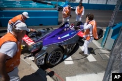 Course officials remove the (37) DS Virgin car driven by Alex Lynn off the track after coming to a stop during Formula E New York City ePrix all-electric auto race, July 16, 2017, in the Brooklyn borough of New York.