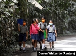 Anak-anak sekolah memakai masker saat berjalan di daerah yang terkena abu vulkanik dari Gunung Agung di dekatnya, di Kabupaten Karangasem, Bali, 29 November 2017. (Foto: REUTERS/Darren Whiteside)