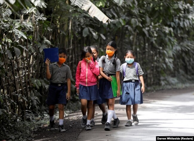 Anak-anak sekolah memakai masker saat berjalan di daerah yang terkena abu vulkanik dari Gunung Agung di dekatnya, di Kabupaten Karangasem, Bali, 29 November 2017. (Foto: REUTERS/Darren Whiteside)