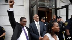 Andrew Wyatt raises his fist as Bill Cosby exits the Montgomery County Courthouse after a mistrial was declared in Norristown, Pa., Saturday, June 17, 2017. Cosby's trial ended without a verdict after jurors failed to reach a unanimous decision. (AP Photo/Matt Rourke)