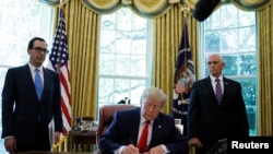 U.S. President Donald Trump signs an executive order imposing fresh sanctions on Iran as Treasury Secretary Steven Mnuchin and Vice President Mike Pence look on in the Oval Office of the White House in Washington, U.S., June 24, 2019. REUTERS/Carlos Barria